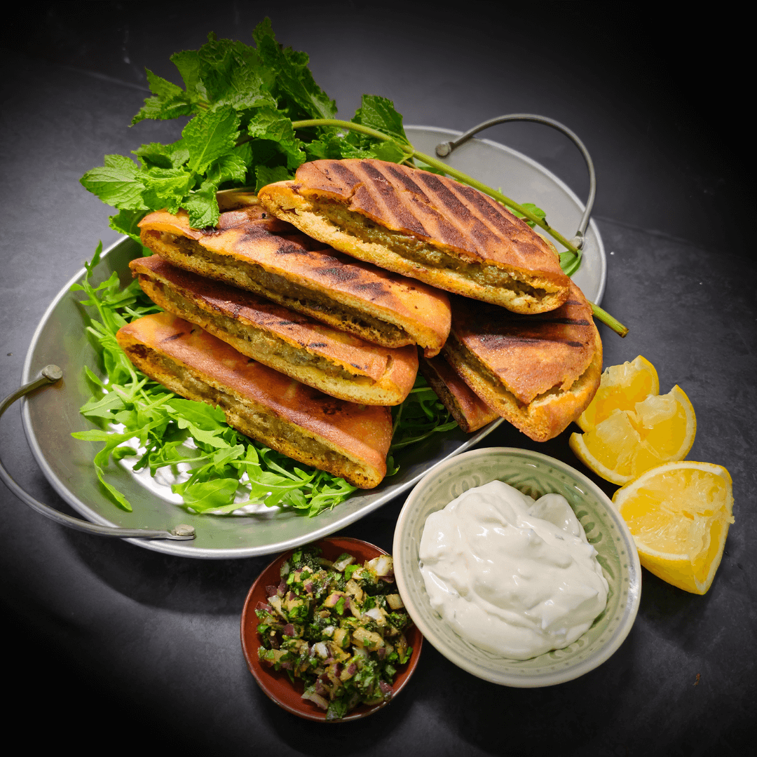 Arayes Libanese pita broodjes gevuld met gehakt, geserveerd met verse kruiden en dips