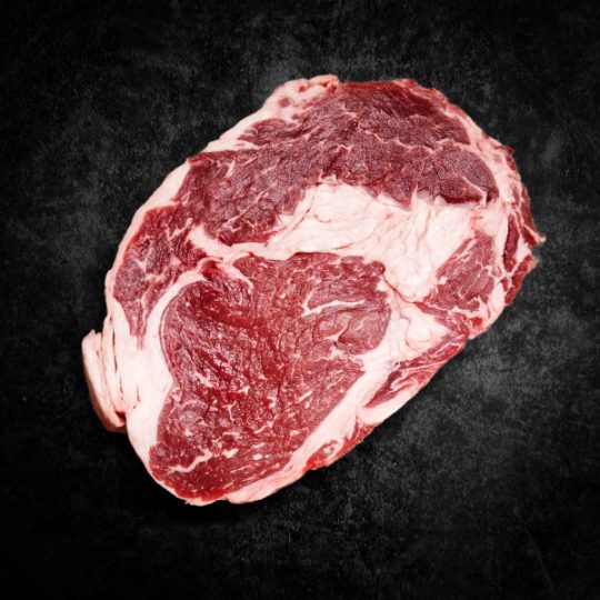 Rauwe ribeye steak met sterke marmering op donkere achtergrond