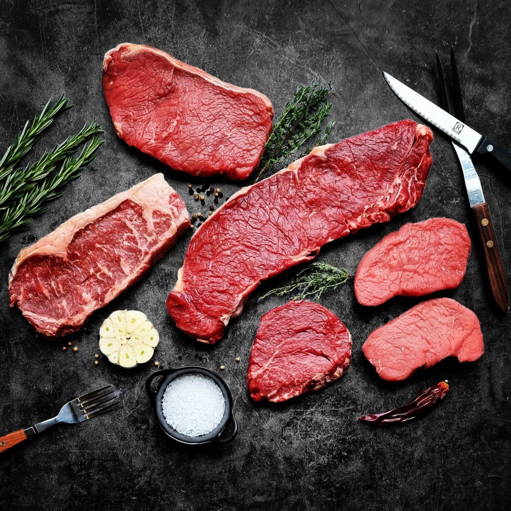 Rauwe rundvlees steaks zoals ribeye, entrecote en biefstuk met kruiden op donkere achtergrond – ambachtelijk rundvlees van Keurslager